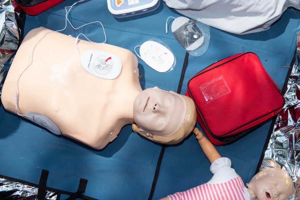 CPR training mannequin with AED pads and first aid kit