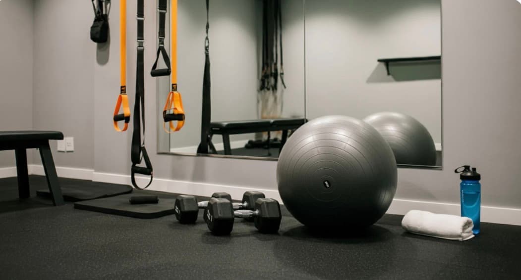 Home gym setup with dumbbells, exercise ball, and TRX straps